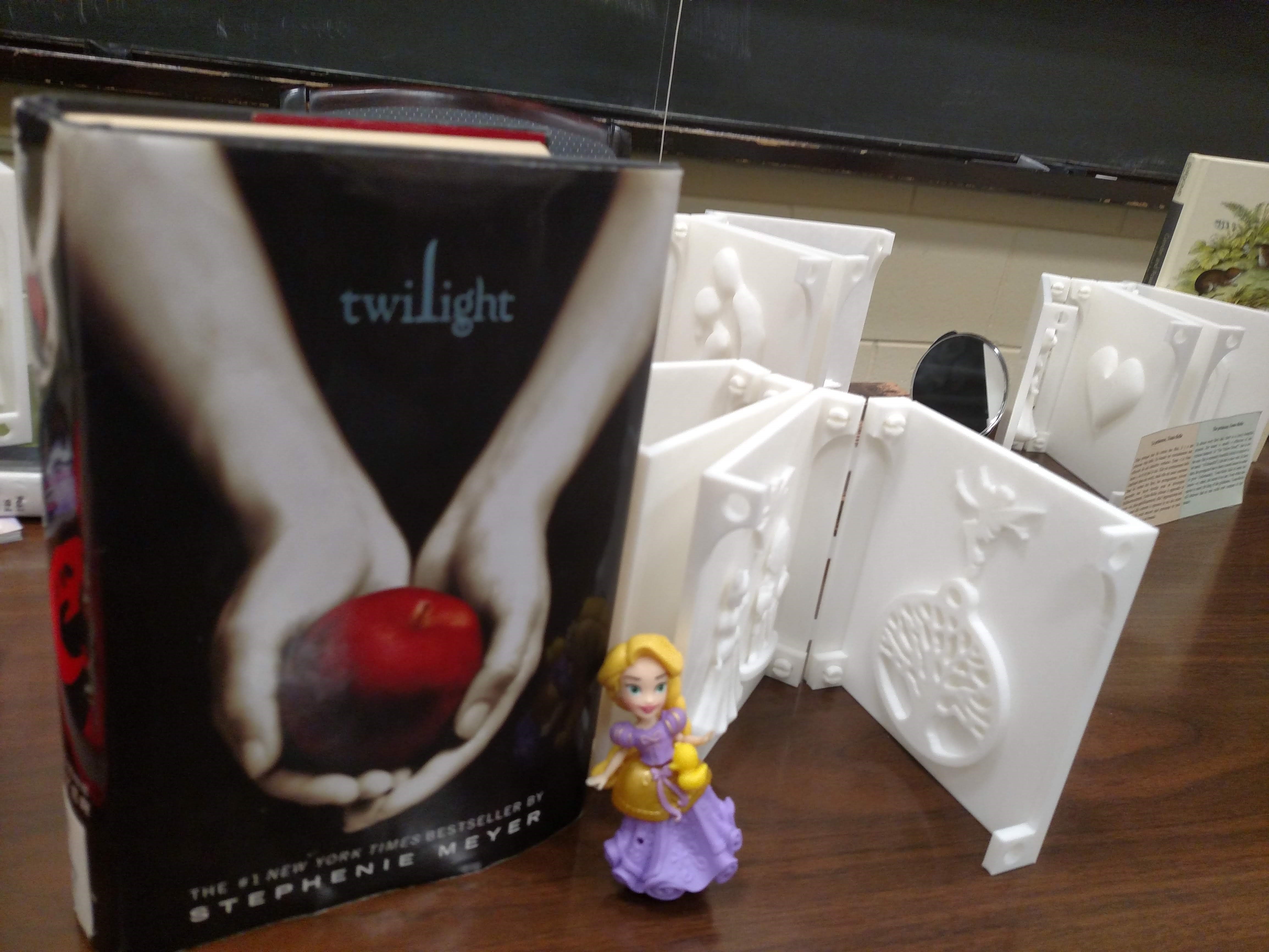 3D book and the book Twilight with a small blond doll in a purple dress